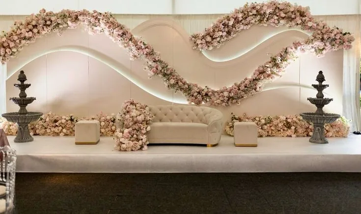 Blush wave backdrop stage with trailing florals and twin fountains
