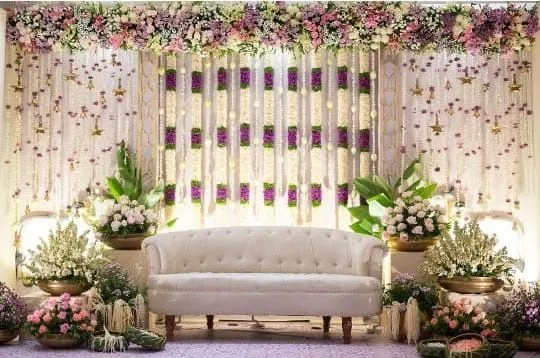 Stage with hanging flower strands, tufted sofa and layered florals