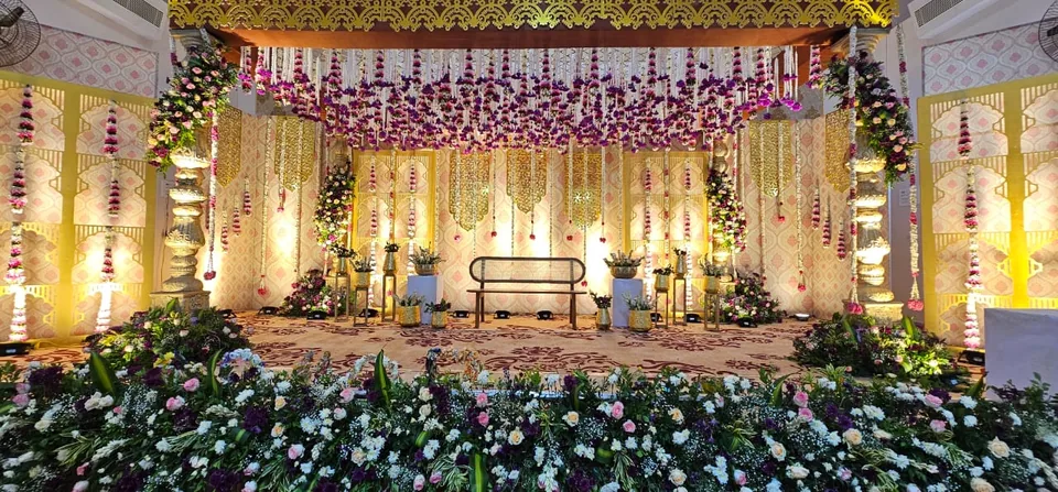 Wide heritage mandap with gold pillars, garlands and silk drapes
