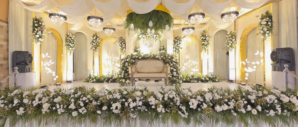 Ivory hall stage framed in garden florals and warm gold light
