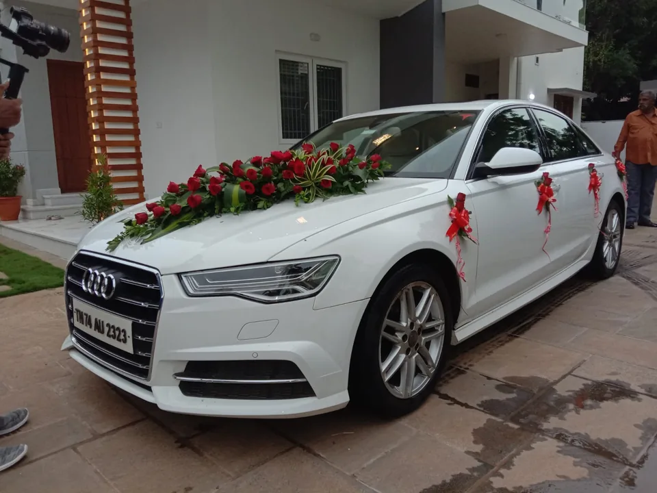 White wedding car with rose garlands and ribbon styling